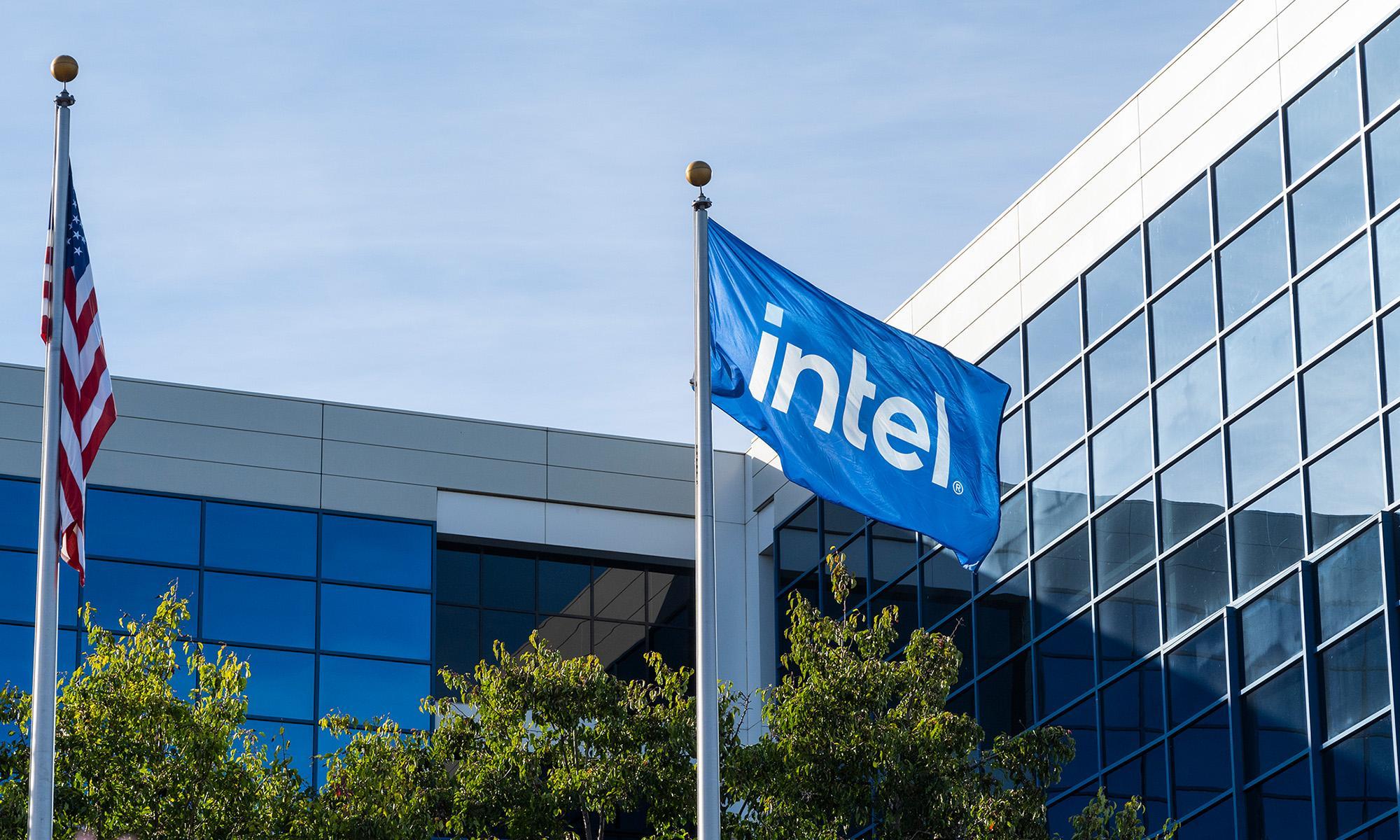 Intel flag flying outside a modern glass office building beside a U.S. flag
