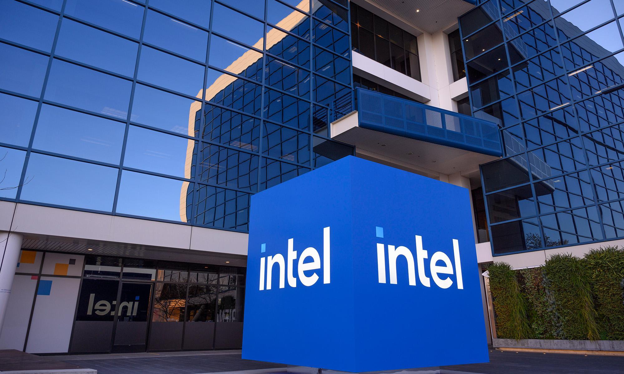 A large blue Intel sign outside a modern glass office building.